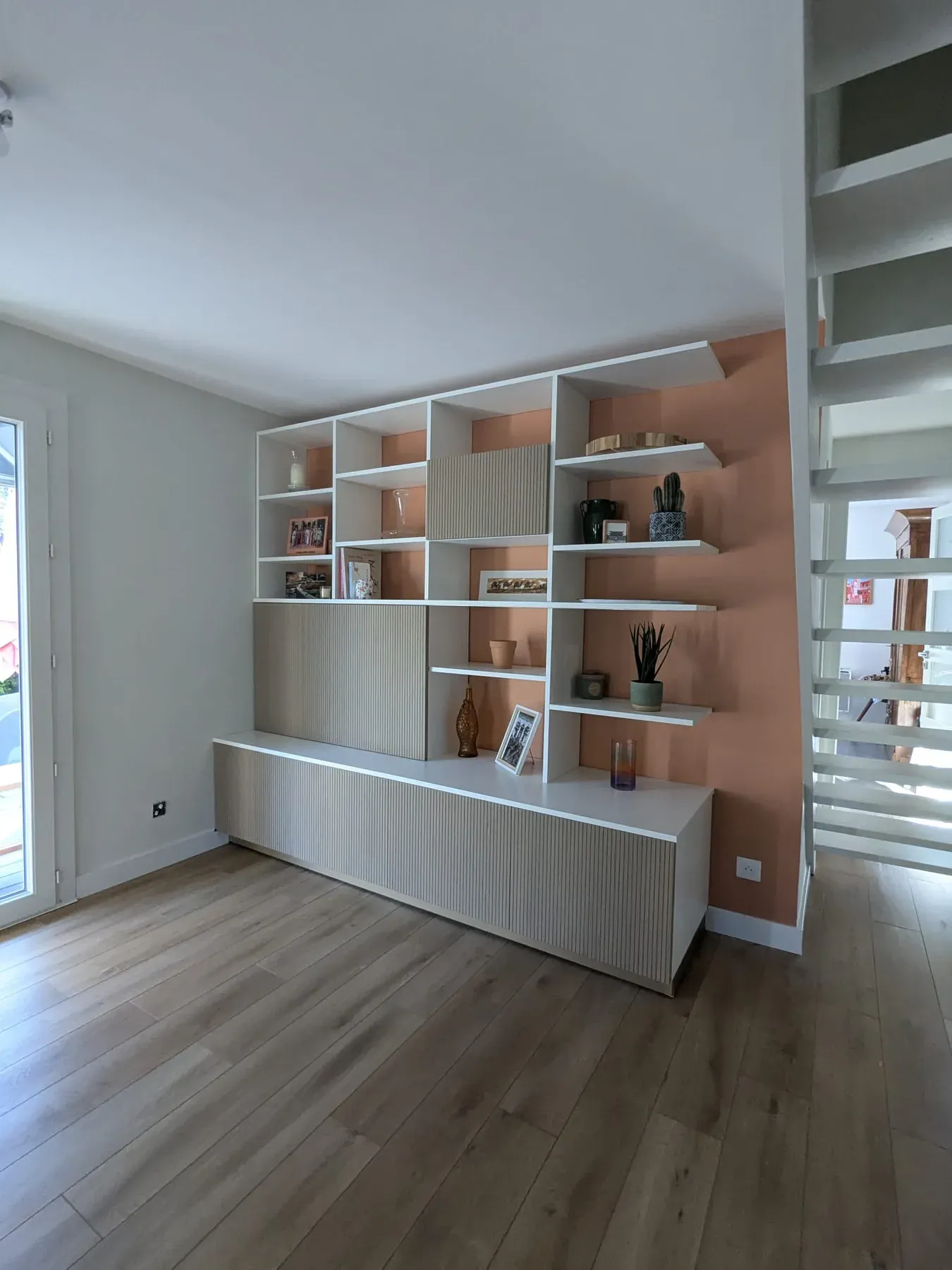 Bibliothèque blanche réalisée devant un mur couleur terre cuite