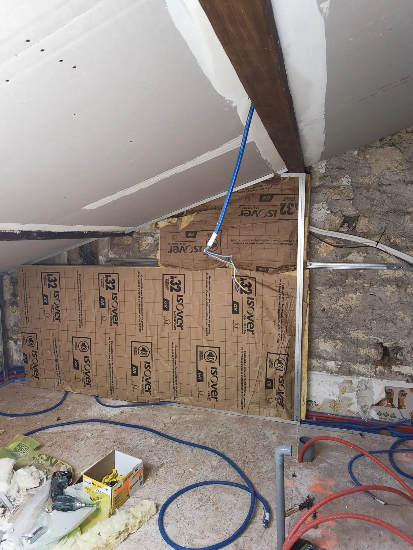 Mur ancien en cours d'isolation sous des poutres apparentes