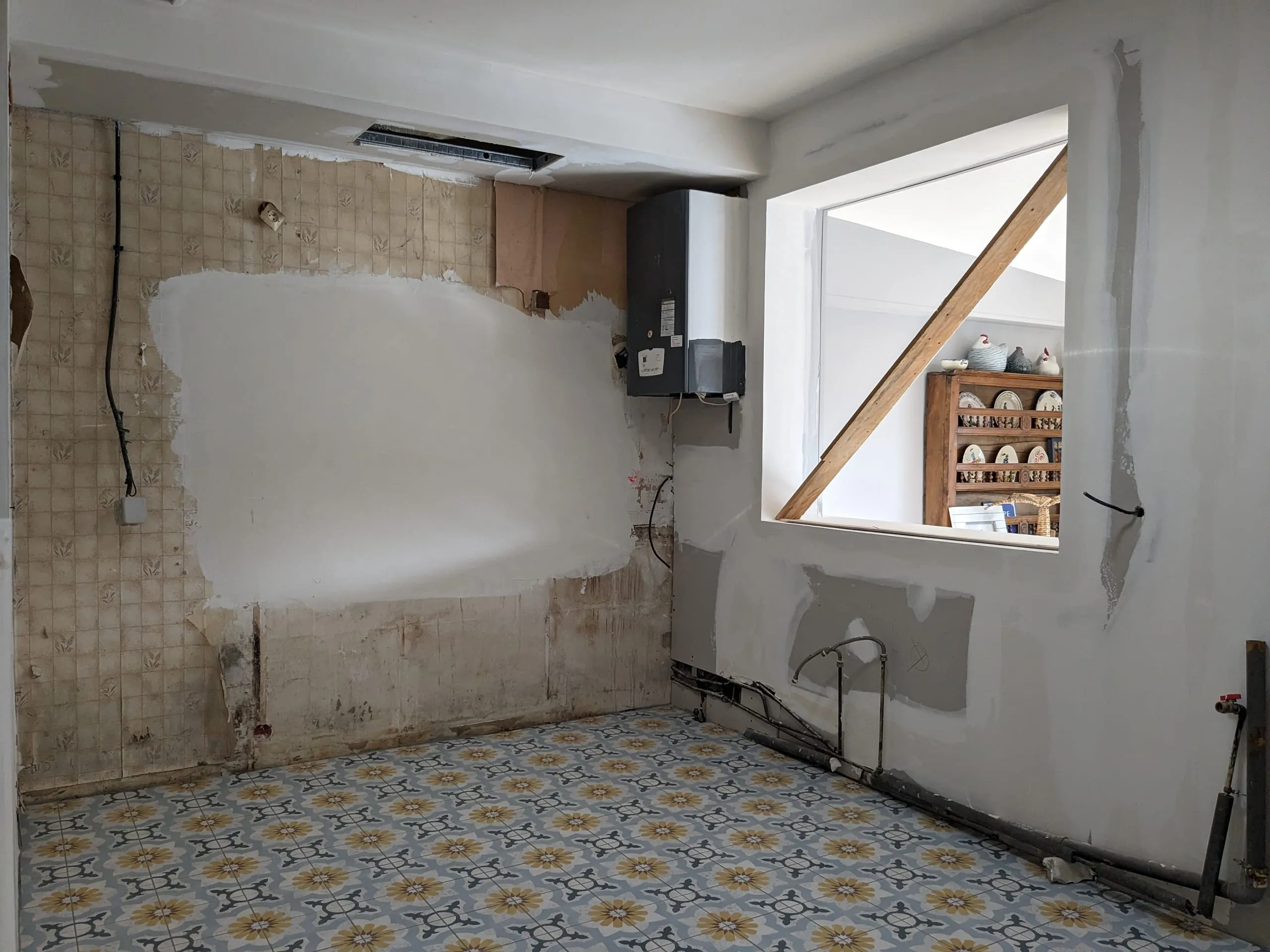 Cuisine en cours de rénovation avec plaques de plâtre, ancien carrelage et sol à motifs